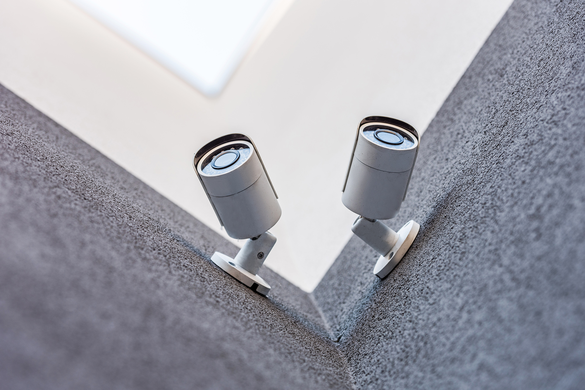 bottom view of two security cameras on wall, security system con